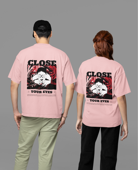 A man and woman wearing matching pink oversized T-shirts featuring the 'Close Your Eyes' painting design on the back, showcasing bold and artistic streetwear style.
