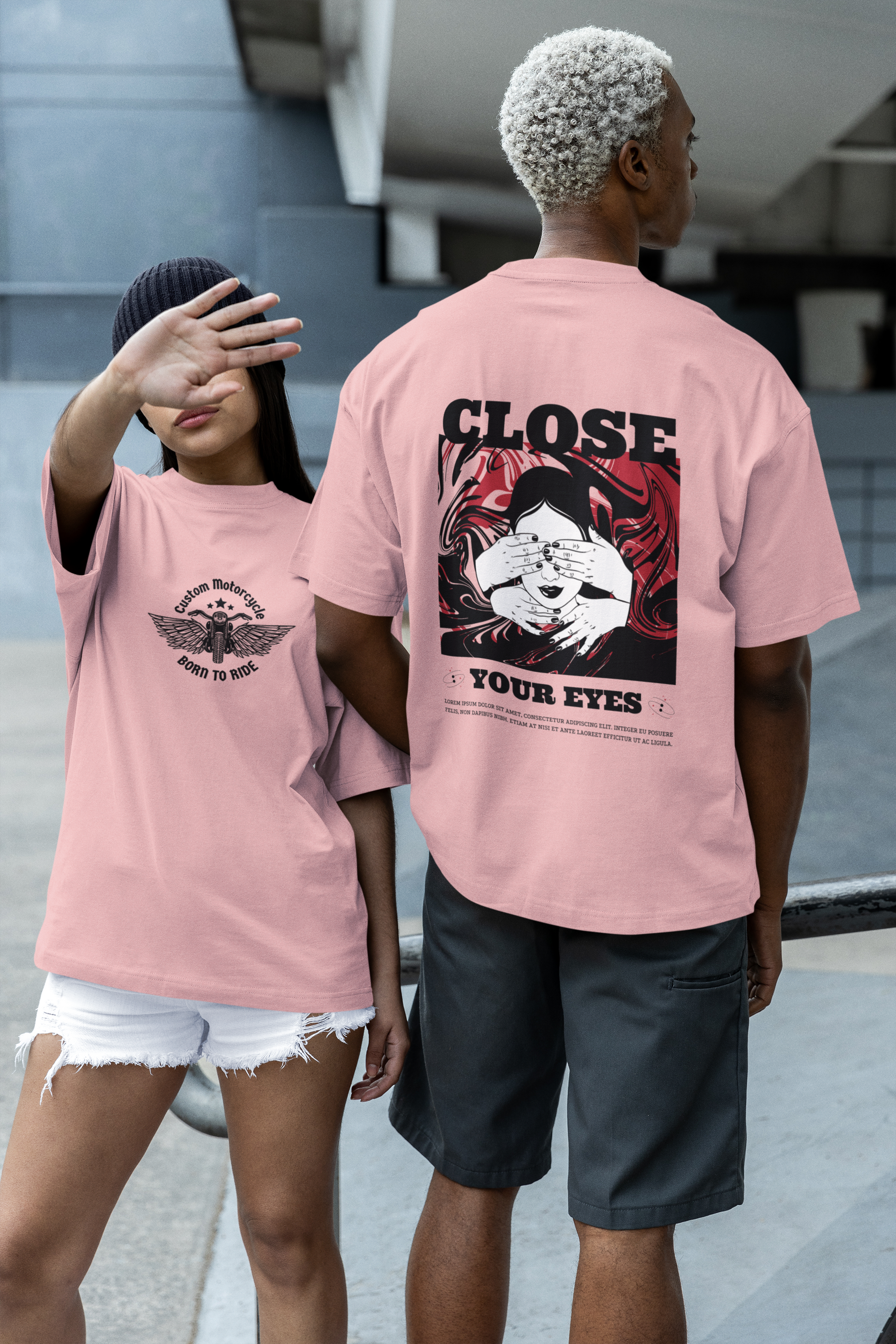 A girl wearing a pink oversized T-shirt featuring the bold 'Born to Ride' quote on the front, paired with a boy in a matching pink oversized T-shirt showcasing the 'Close Your Eyes' painting design on the back, creating a stylish and coordinated streetwear look.