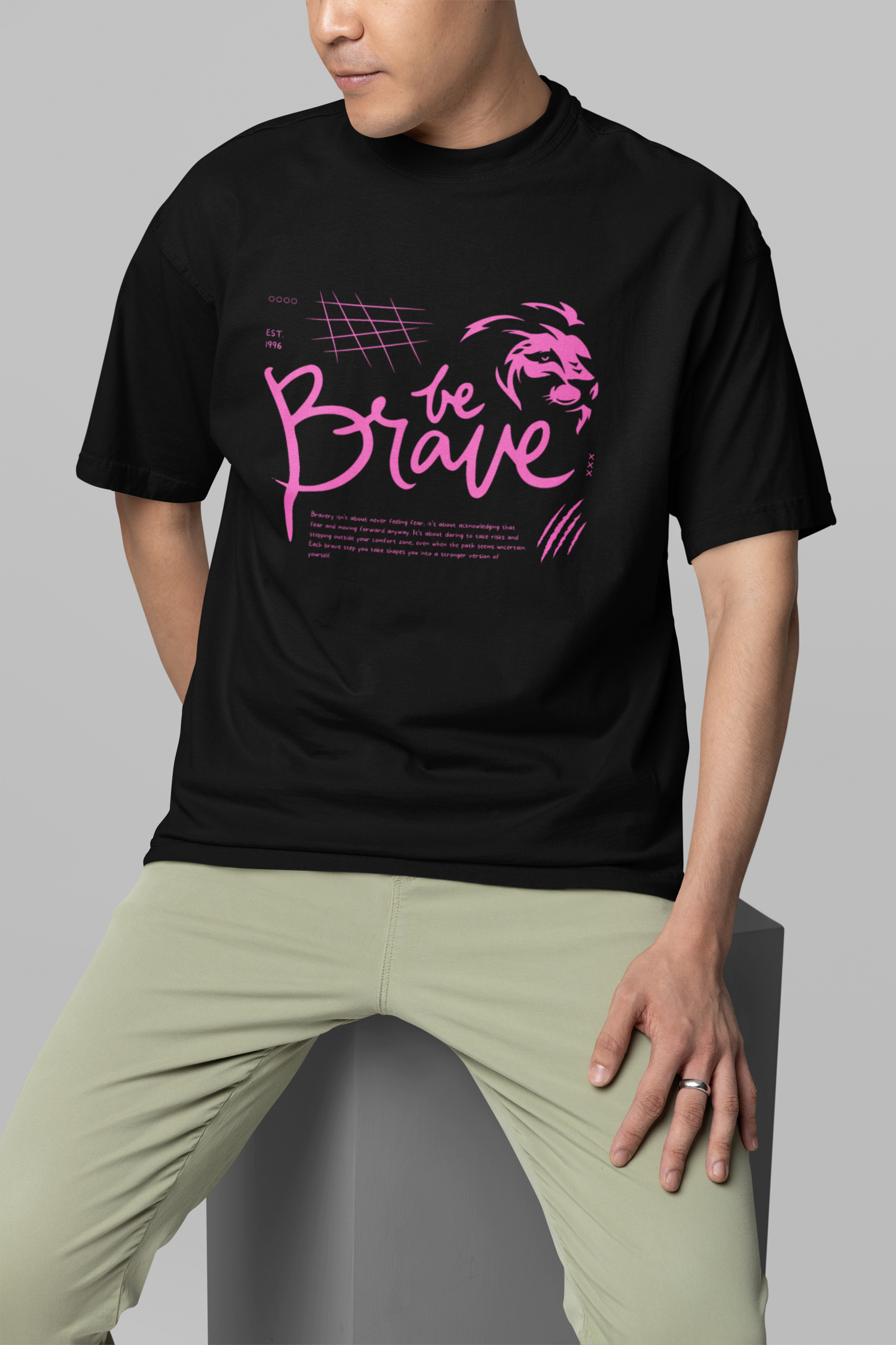 A boy standing confidently in a black oversized T-shirt featuring the 'Be Brave' text and lion logo, perfect for bold and motivational streetwear by Looma Fashion.