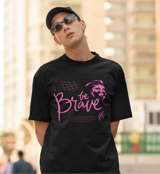 A boy wearing a black oversized T-shirt featuring the bold 'Be Brave' text and lion logo on the front, showcasing motivational streetwear by Looma Fashion.