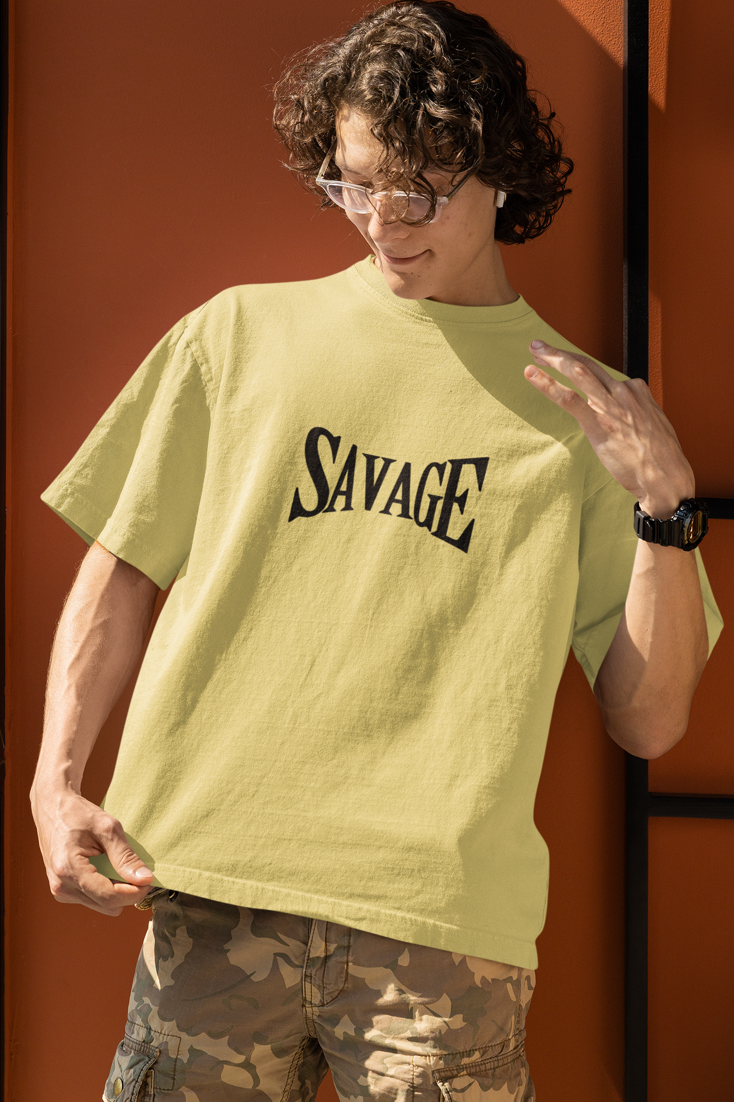 A boy wearing a yellow oversized T-shirt with bold 'Savage' typography on the front, perfect for making a bold streetwear statement by Looma Fashion.
